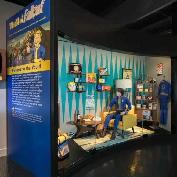"World of Fallout" exhibit featuring a Vault-Tec diorama with a mannequin in a Vault suit and retro memorabilia.
