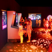 Visitors exploring the immersive Atomic Odyssey exhibit at the Atomic Museum in Las Vegas, featuring interactive STEM displays and vibrant lighting.