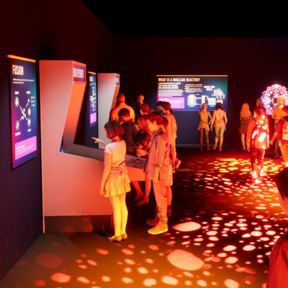 Visitors exploring the immersive Atomic Odyssey exhibit at the Atomic Museum in Las Vegas, featuring interactive STEM displays and vibrant lighting.