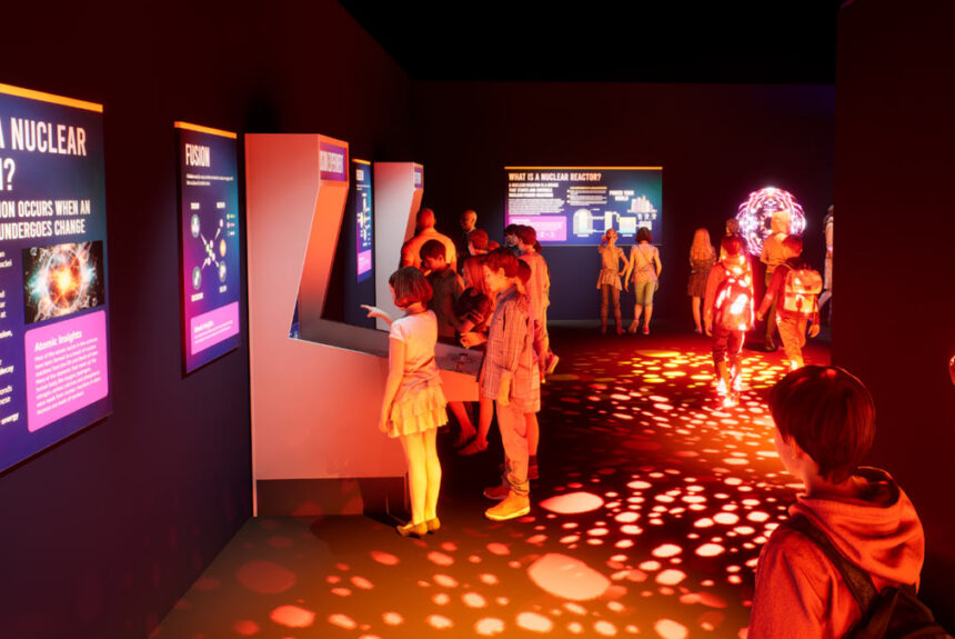 Visitors exploring the immersive Atomic Odyssey exhibit at the Atomic Museum in Las Vegas, featuring interactive STEM displays and vibrant lighting.