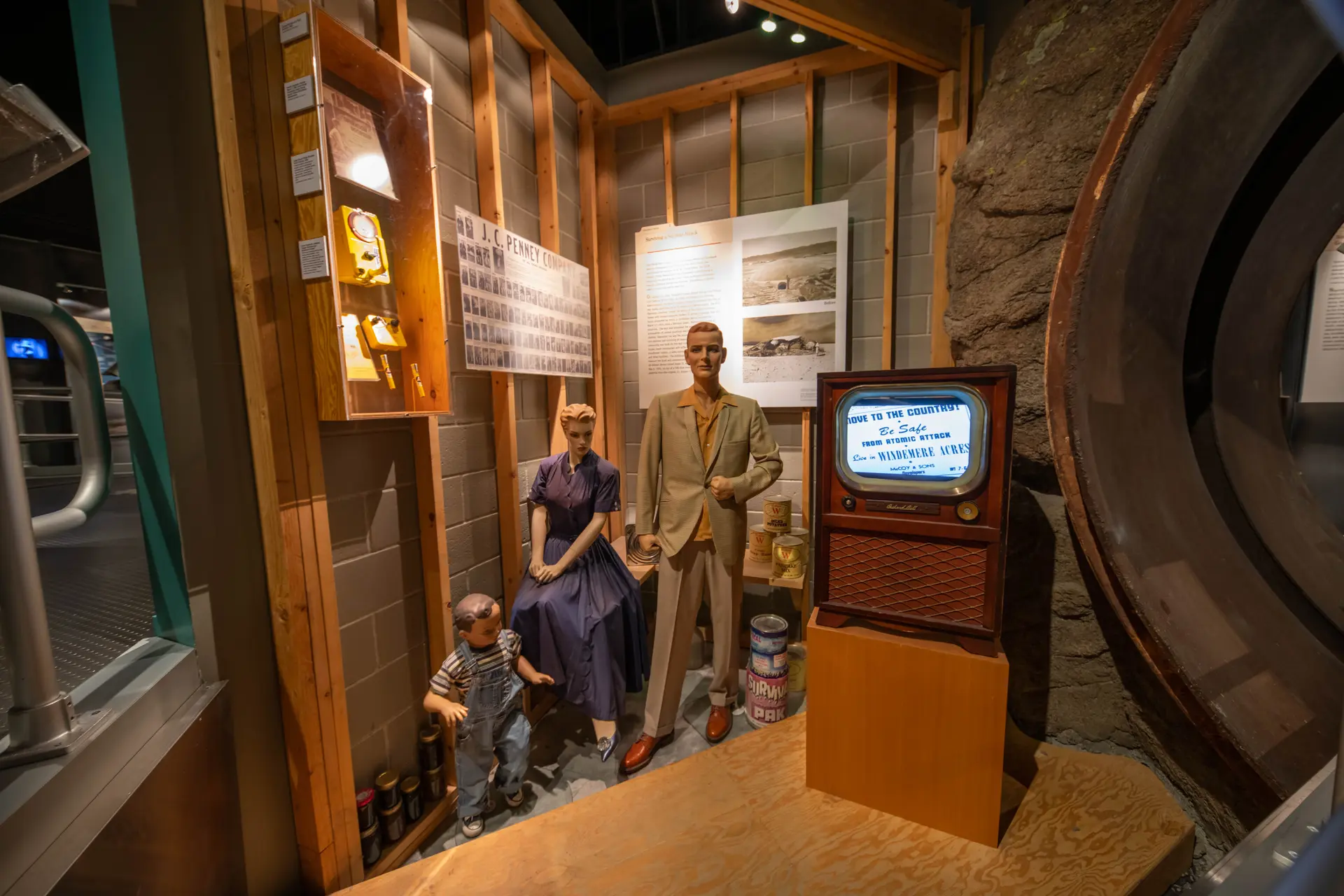 Family mannequins in a 1950s bomb shelter exhibit next to a vintage television.