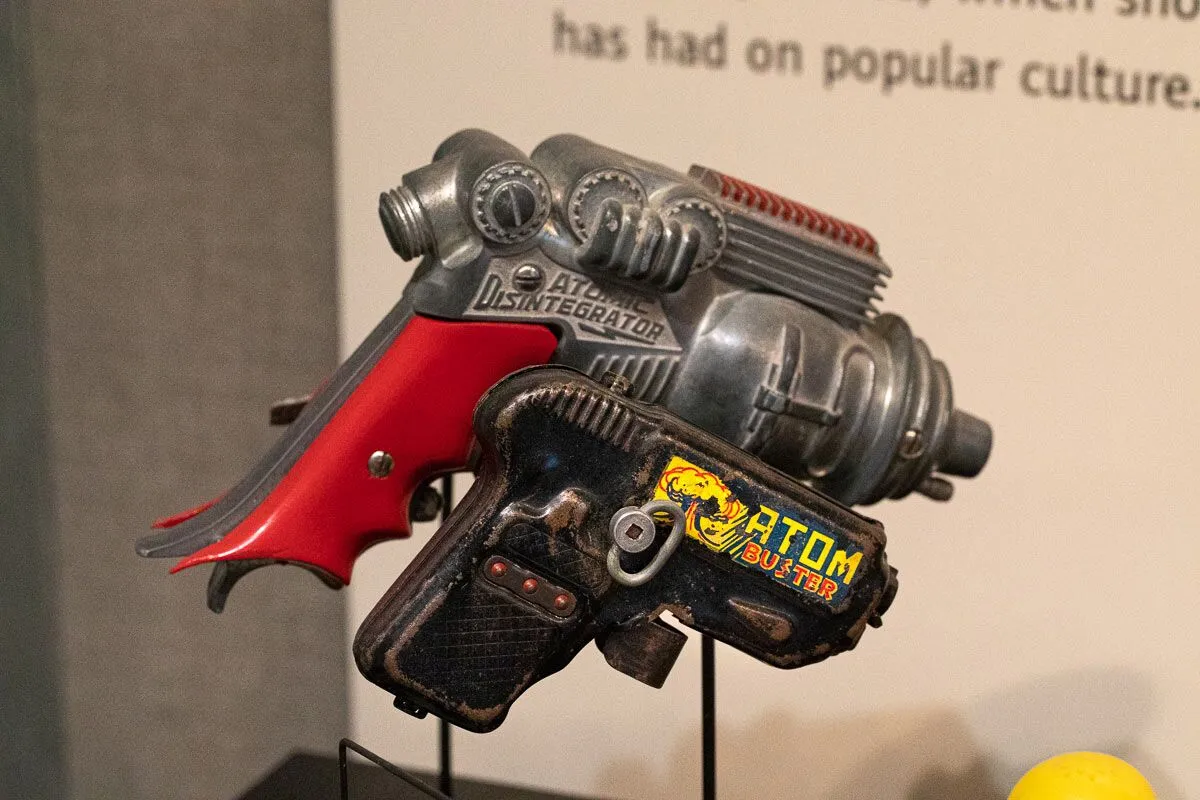 Vintage toy ray guns labeled "Atomic Disintegrator" and "Atom Buster."