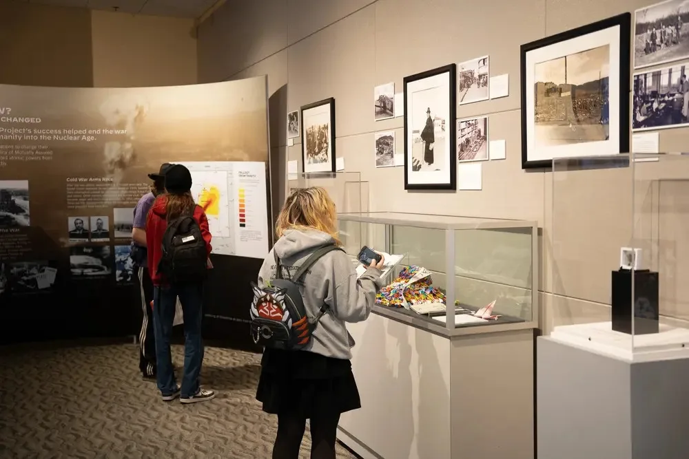 Visitors viewing framed historical photographs and artifacts in a museum gallery