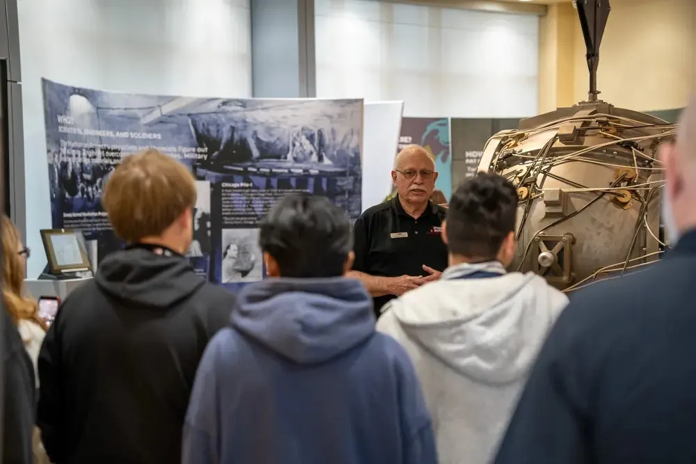 Group of students watching a video projection of a nuclear blast in a museum exhibit