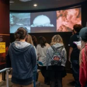 A group of students watching historical nuclear testing footage during educational field trips at the Atomic Museum.