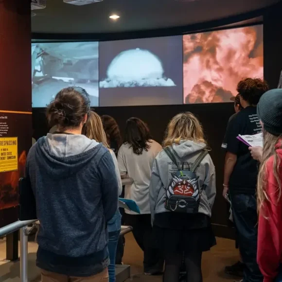 field-trips-at-the-atomic-museum A group of students watching historical nuclear testing footage during educational field trips at the Atomic Museum.